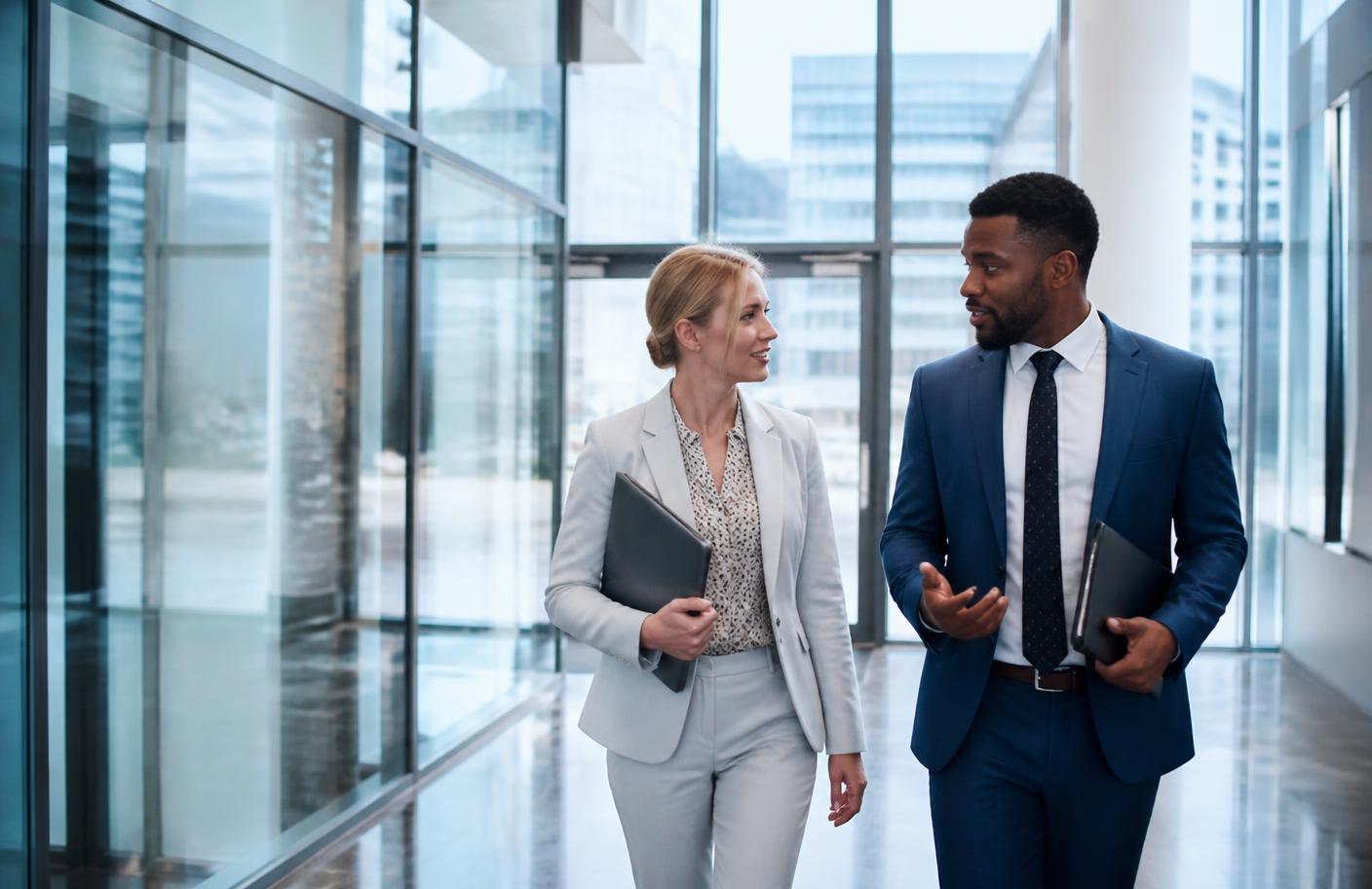 Two business partners walking through an office lobby with financing documents